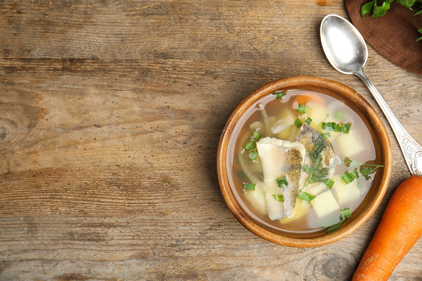 Delicious fish soup served on wooden table, flat lay. Space for text