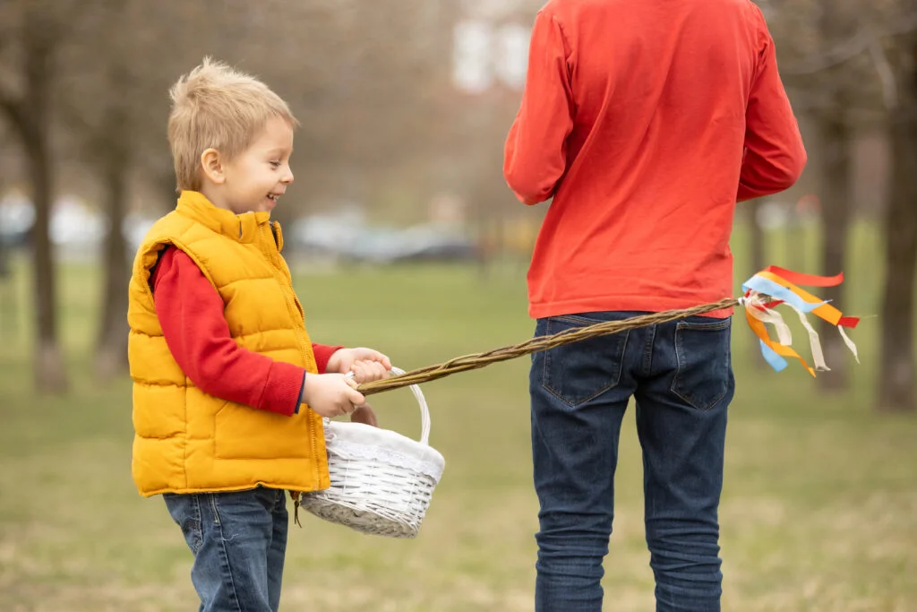 Cute preschool child, whipping his sister on Easter with twig, braided whip made from pussy willow, traditional symbol of Czech Easter used for whipping girls and women