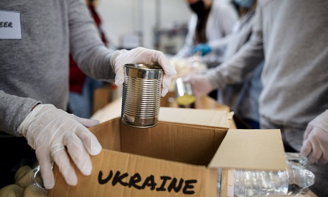 Group of volunteers collect donations for Ukrainian refugees, humanitarian aid concept.
